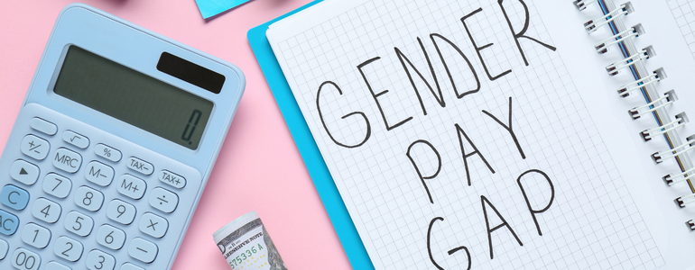 The Gender Pay Gap; written on a notepad, next to a calculator, on a pink and blue background.