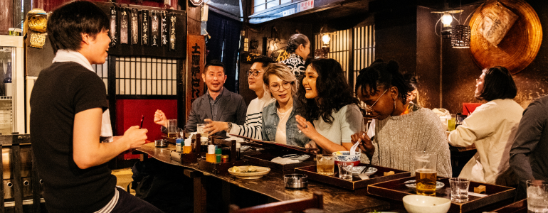 Tourists eating in a traditional Japanese Izakaya restaurant.