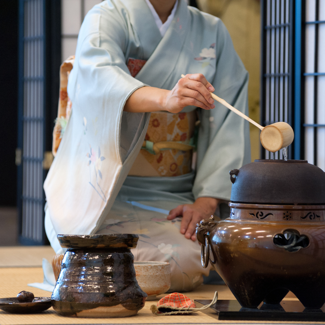 Woman making matcha in a traditional Japanese tea ceremony wearing a kimono.