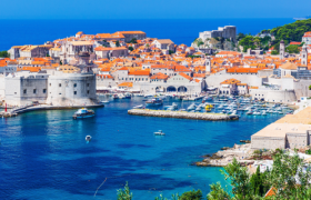Croatia Travel Advice: How much does it cost to travel Croatia like a Travel Guide? Image shows blue oceans and ancient city of Dubrovnik, Croatia.