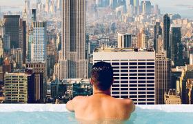 man in swimming pool overlooking city view